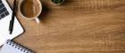 Photo of a wooden table with coffee, a notepad and pen