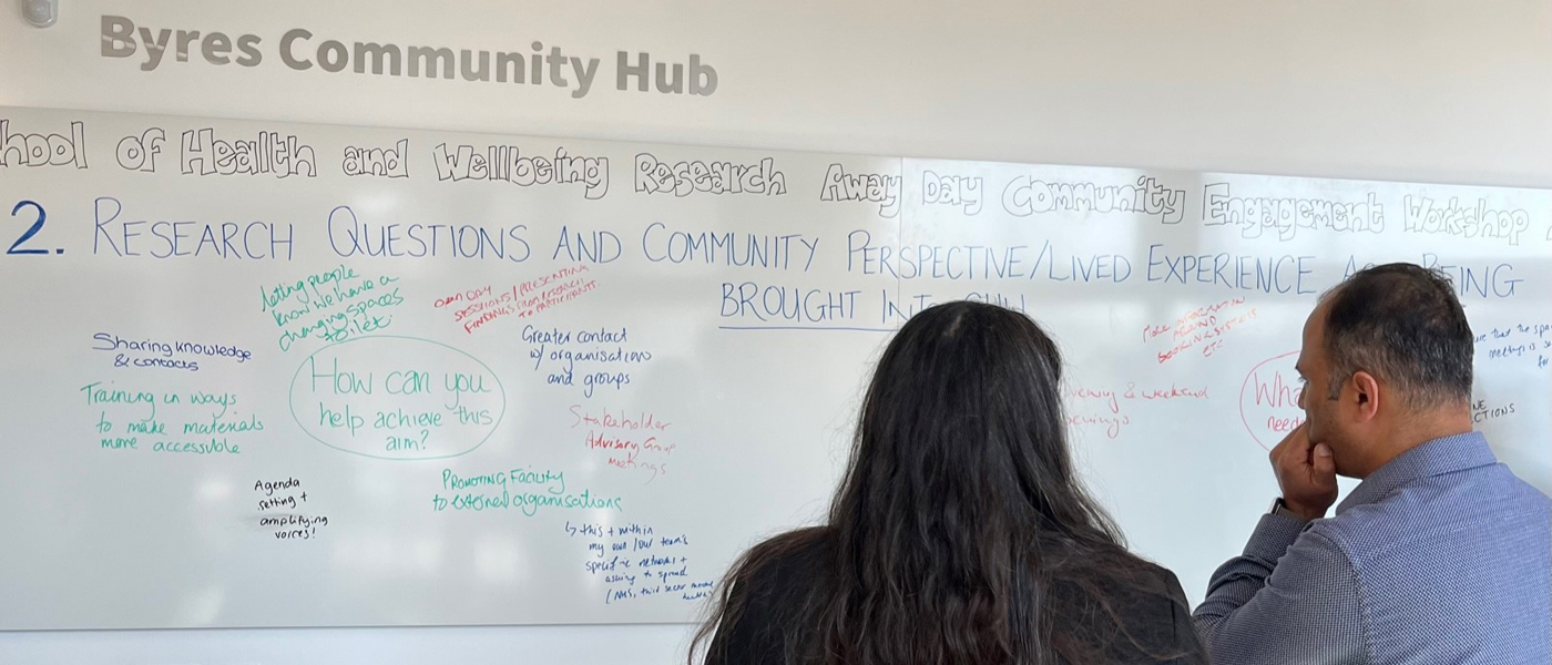 2 School of Health and Wellbeing colleagues look at a whiteboard of ideas for community engagement in the Byres Community Hub in the Clarice Pears building