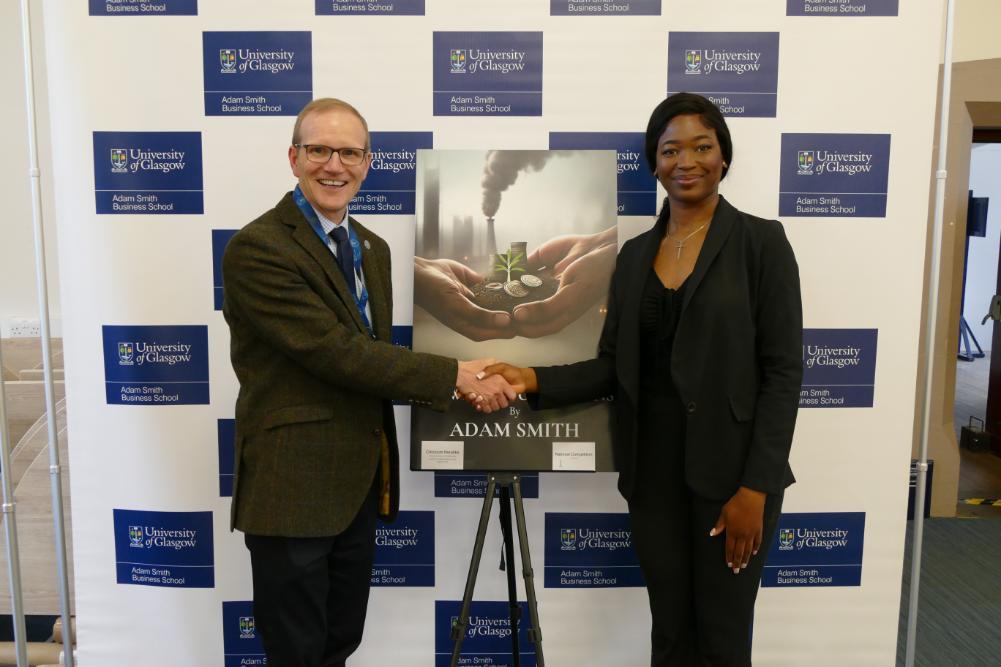 Professor Graeme Roy shaking hands with Chizulum Ifezulike across the winning national competion cover image with two hands holding a growing tree in soil and coins with a skyscraper behind. Source: ASBS