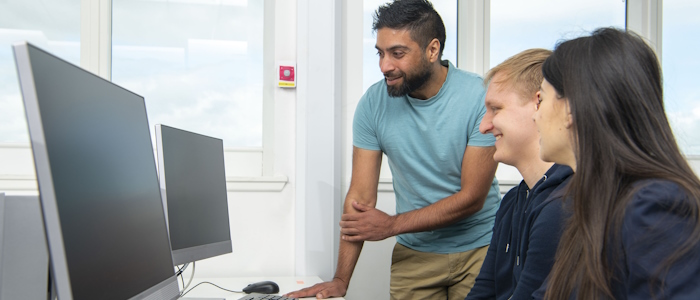 Three students looking at a monitor in computing class