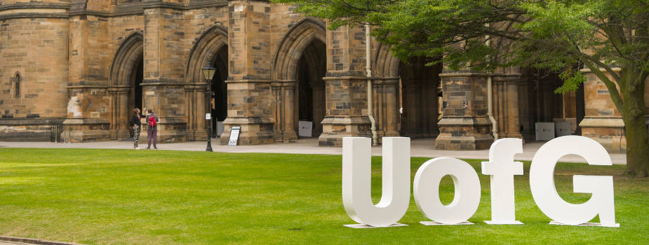The large white UofG letters in the courtyard of the main building, with the cloisters in the background