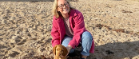 Photo of UofG staff member Margaret Thomson standing on a beach with a tiny puppy