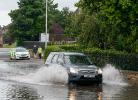 A silver car drives through a flooded road in scotland