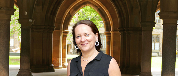 Carol Andrews standing outside the main building at the University of Glasgow
