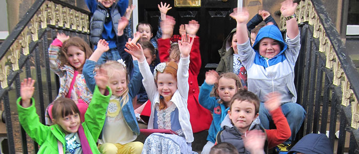 Primary school children sitting on steps waving