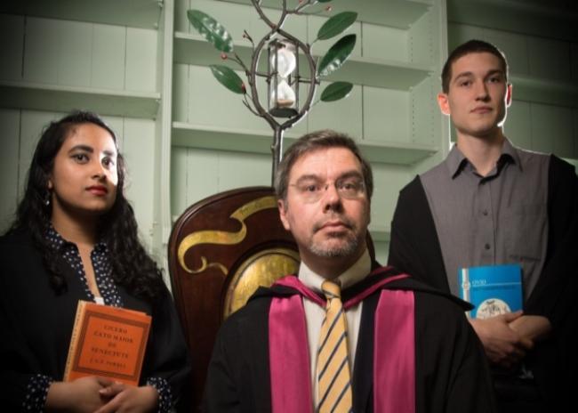 Latin student Hirushi Wickramaratne ; Professor of Latin Costas Panayotakis seated on the Blackstone Chair and Latin student and winner of the 2018 Cowan Blackstone Medal Charles Figes.