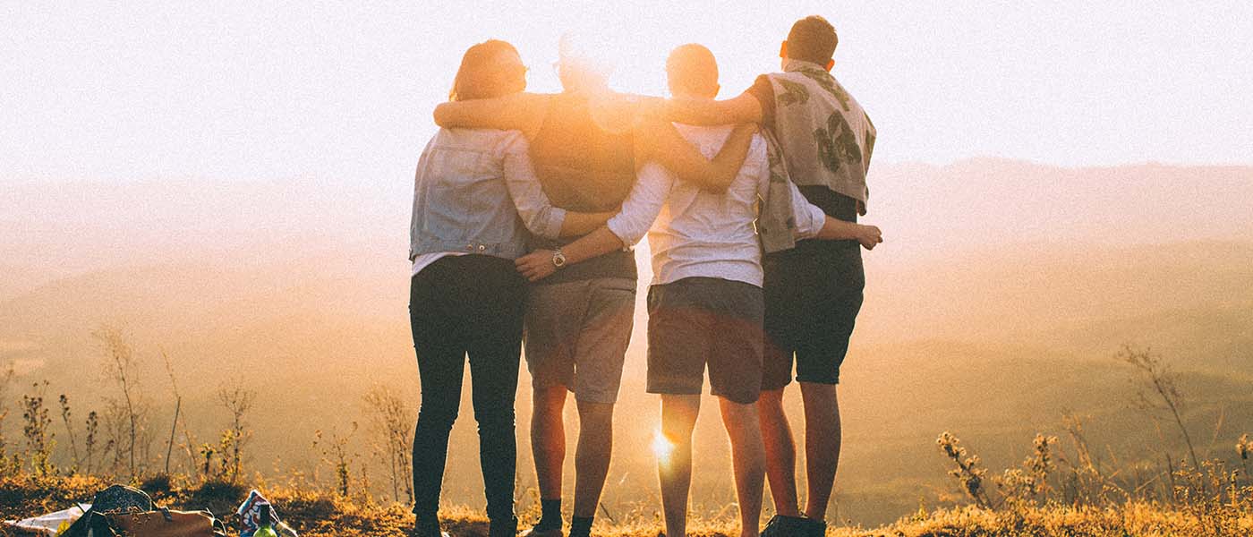 Back shot of a group of four friends looking at a low sun