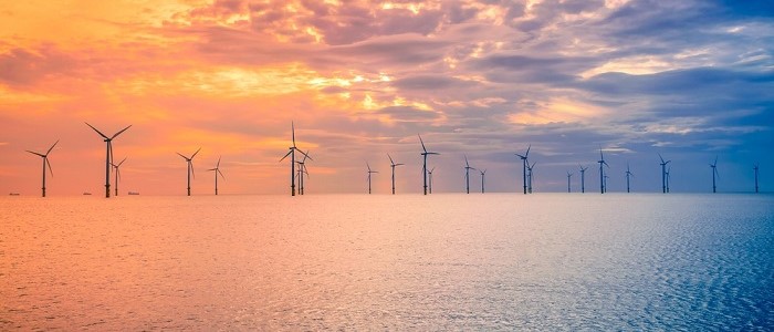 An image of a wind farm off the coast of the UK at sunset